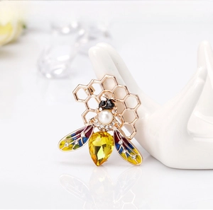 Detailed macro view of bee brooch with colorful enamel wings and yellow gemstone