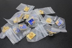 Detail of bulk-packed Australia flag metal pins in clear polybags with secure pin backs