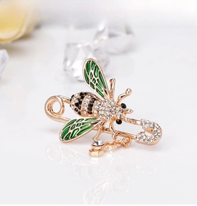 Macro shot of bee safety pin brooch with green enamel wings and crystal drop charm