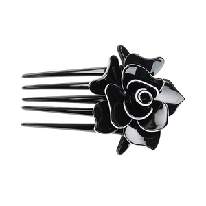 Detail of a shiny black acrylic flower hair comb with white edges and five teeth design
