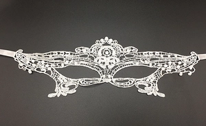 Detailed view of white lace masquerade mask with intricate cutout patterns on gray background