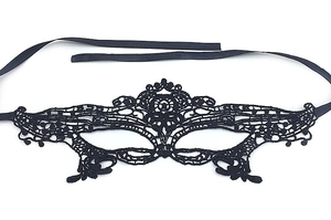 Close-up of black hollow lace masquerade mask with intricate butterfly patterns and satin ties