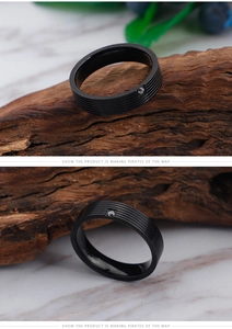 Macro detail of black titanium ring with five parallel grooves and a centered clear zircon