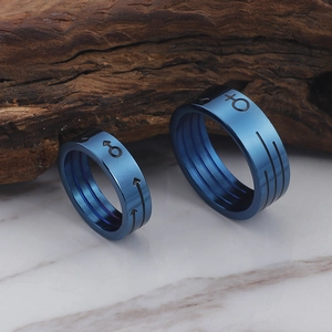 Blue titanium steel couple rings with Mars and Venus symbols on marble surface