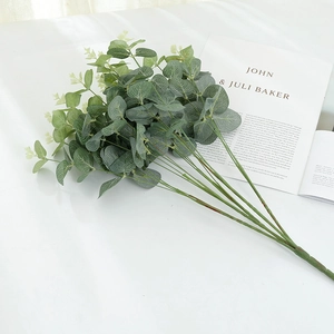 Close-up of artificial eucalyptus leaves with realistic silk texture on a white desk
