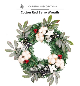 Détail d'une couronne de Noël avec boules de coton, baies rouges et nœud rayé doré