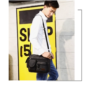 Detail of black canvas messenger bag featuring functional pockets and adjustable nylon strap