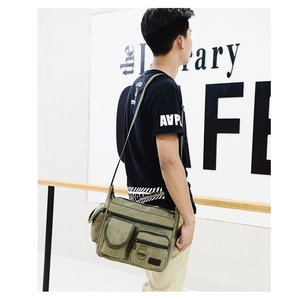 Detail of army green canvas crossbody bag featuring multi-pocket design and durable base