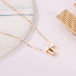 Chic gold heart and letter D pendant necklace on a minimalist marble background