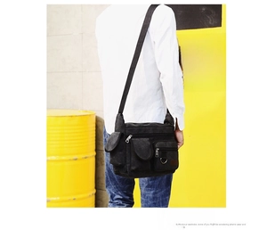 Rear view of a black canvas crossbody bag for men with multi-pocket design on industrial background