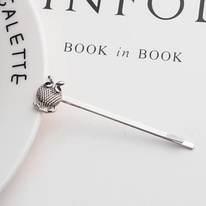 Silver owl hair clip with intricate mesh texture and sparkling eye detail on books
