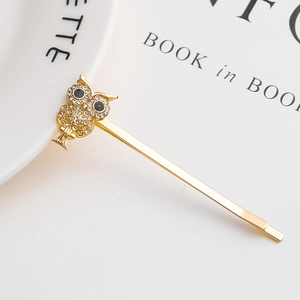 Close-up of a golden alloy owl hair clip set with sparkling crystals and black eyes