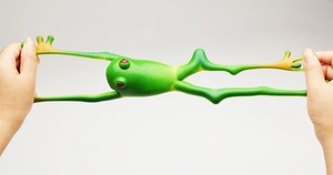 Elastic green frog squeeze toy being stretched by hands to show high resilience