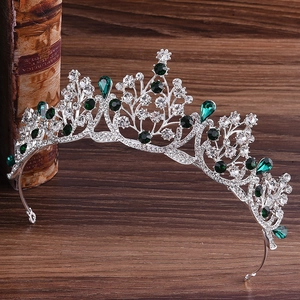 Détail de la couronne de mariée argentée avec cristaux verts sur fond de bois