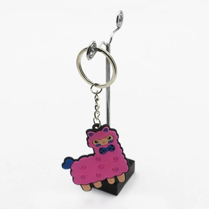 Pink PVC alpaca keychain with silver metal ring and blue bow tie detail on white background