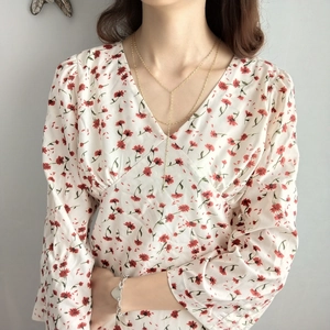 Detail of elegant gold double-layer Y-shaped necklace on floral V-neck dress