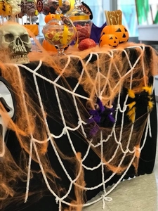 Halloween table setting with black spiderweb cloth, orange cotton, and skull props