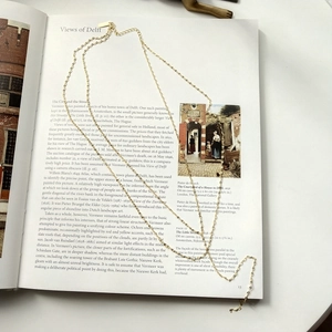 Detail of elegant gold double-layered necklace placed on an artistic book page