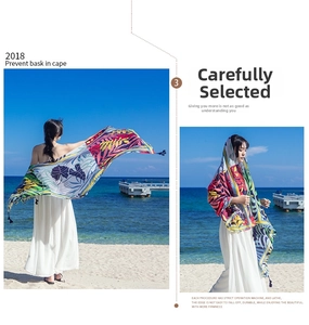 Detail of vibrant tropical leaf print beach shawl on a sunny coast with ocean backdrop