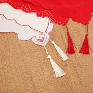 Detail of red and cream Christmas table runner with festive embroidery and silk tassels