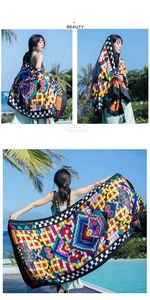 Detail of vibrant geometric patterned scarf with black check borders and tassel accents
