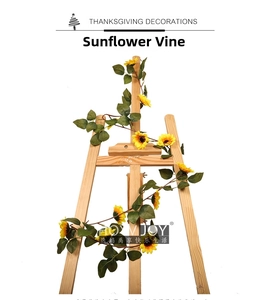 Detail of yellow artificial sunflower vine with green leaves wrapped on wooden easel