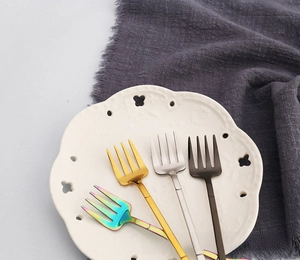 Detailed shot of stainless steel dessert forks in gold, silver, black and neon finishes