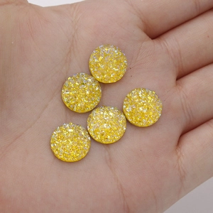 Detailed close-up of 12mm golden yellow resin cabochons with sparkling glitter finish