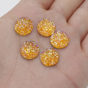 Detail of 12mm yellow resin star glitter rhinestones held in hand for size scaling