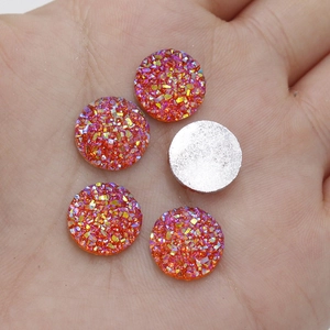 Close-up of 12mm orange resin druzy crystals with flat back on palm for DIY jewelry