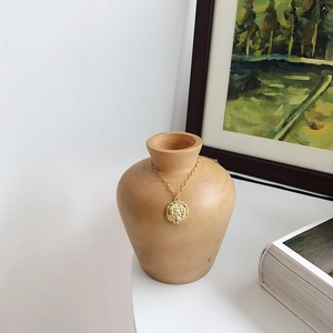 Artistic close-up of a gold vintage coin pendant featuring a classical relief on a vase