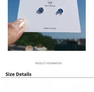 Detailed view of silver planet and moon earrings with blue enamel finish