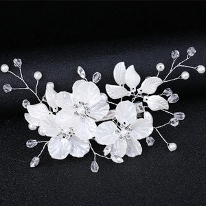 Elegant bridal hair clip with white shell flowers, pearls and crystals on dark backdrop