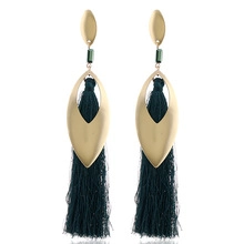 Detailed view of long gold leaf earrings with green beads and silky fringe tassels