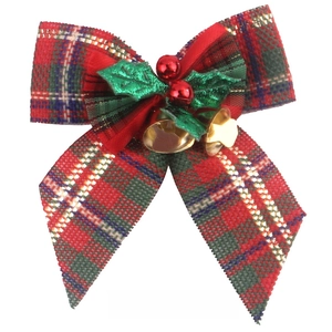 Detail of red and green plaid linen Christmas bow with golden bells and berries