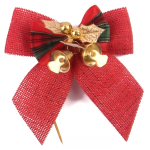 Detail of red burlap Christmas bow with gold bells and festive leaf decoration
