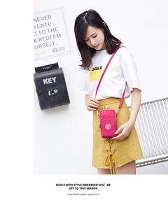 Detail view of pink nylon crossbody phone bag with multi-zipper layers on a model