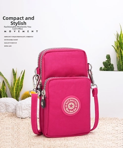 Detailed view of magenta mini phone bag with three zippered compartments on sand background