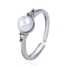 Detail of adjustable silver ring featuring a white pearl and side crystal accents