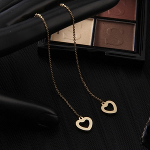 Detailed view of elegant gold heart tassel earrings hanging on a black display stand