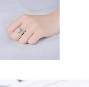 Close-up of minimalist silver star ring with small bell charm on hand with soft background