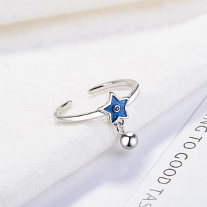 Minimalist adjustable silver ring with blue star pendant and tiny bead on white fabric