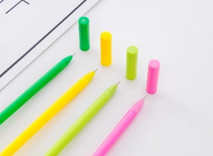 Close-up of four colorful watermelon-shaped gel pens with caps on a clean white paper background