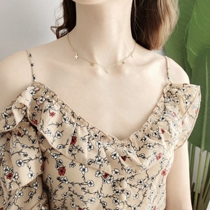 Close-up of minimalist gold choker necklace with tiny cross and star charms on model