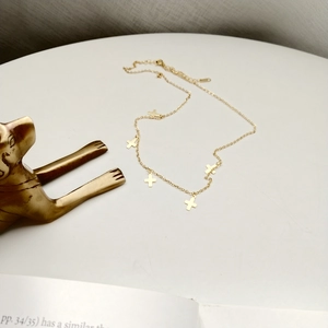 Detail of a minimalist gold cross pendant necklace on a clean, elegant background