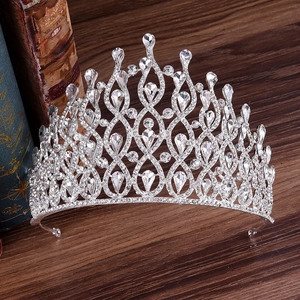 Silver bridal crown with luxury crystals on vintage books and dark wood background