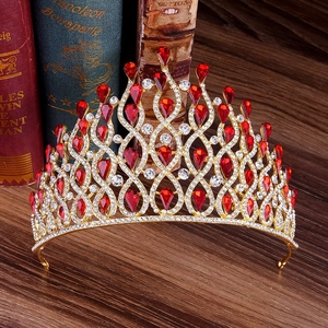 Macro detail of luxury gold crown with red teardrop gems and clear crystals on vintage books