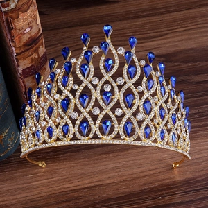 Detailed shot of golden bridal crown with blue teardrop gems on vintage books