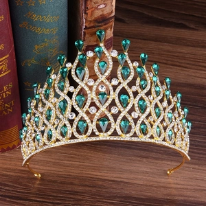 Detailed macro of golden luxury crown with green teardrop gems and white crystals