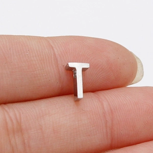 Close-up of a 10mm polished stainless steel letter T bead held between fingers